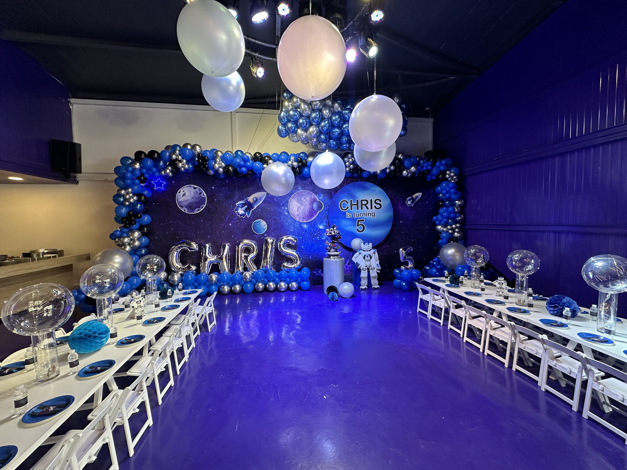 A Recreo birthday room decorated with balloons, tables, and a themed backdrop