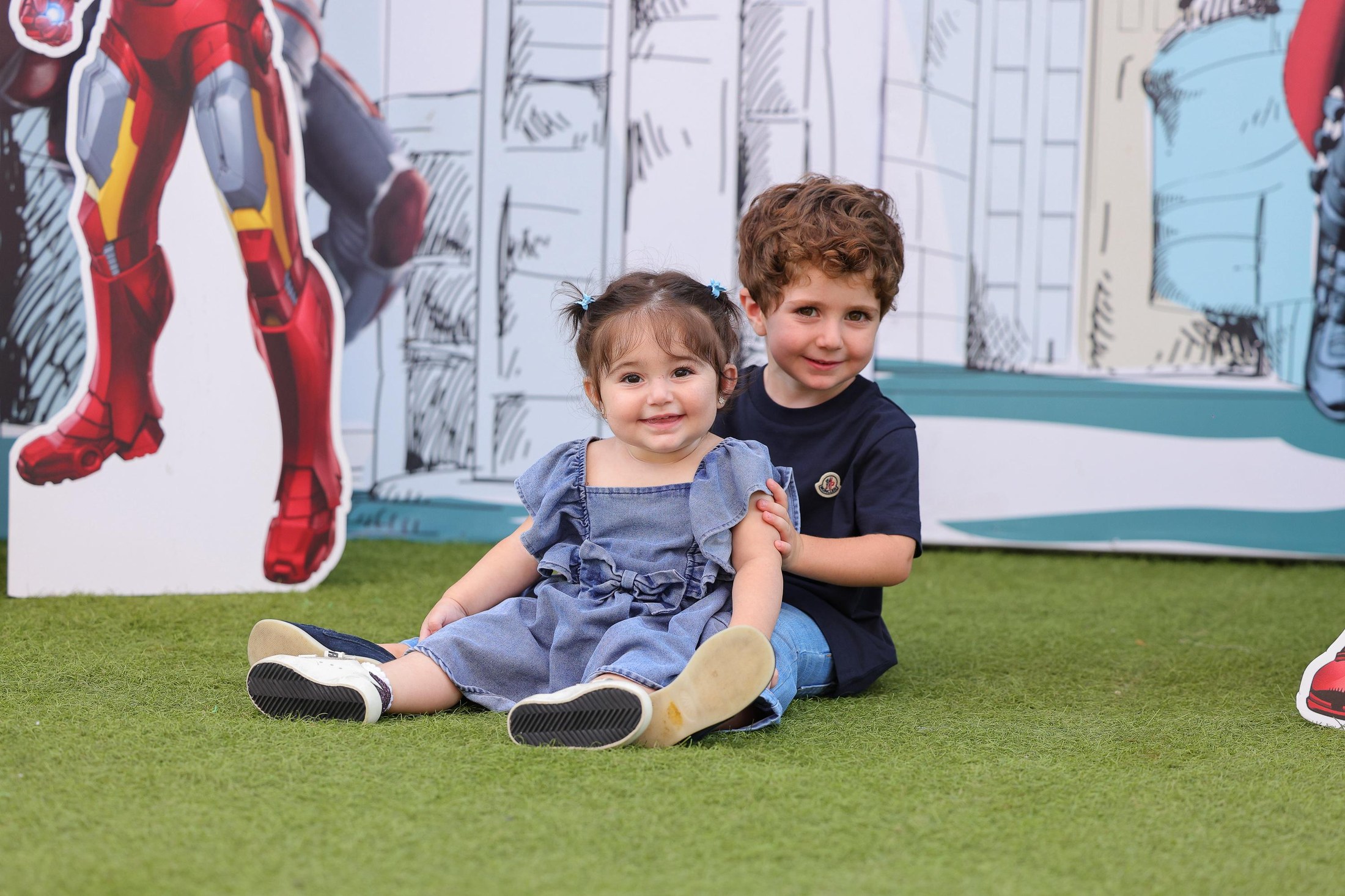 Children smiling on Recreo turf in front of the superhero birthday setup